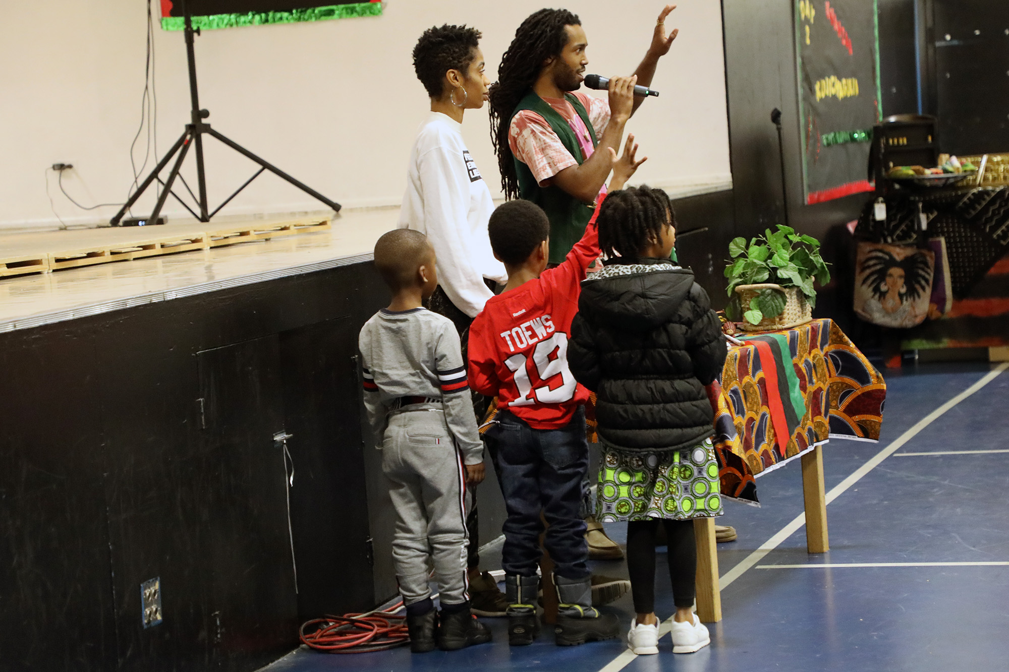 SuperGroup members Imani Amos and Ayinde Cartman explain the principles of Kwanzaa and how to properly light the kinara — the candle holder used in Kwanzaa celebrations. (Arionne Nettles/WBEZ)