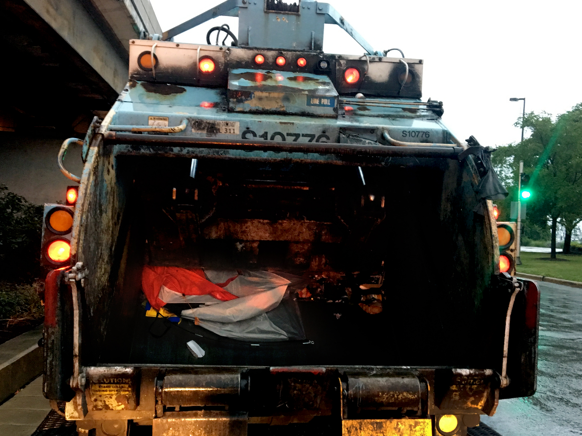 Once Streets and Sanitation workers throw Smith and Moore’s tent in a city garbage truck, the police officers and other city employees leave. Smith and Moore said they will spend the next few hours panhandling to purchase a new tent that they will put up in the same location that night. (Odette Yousef/WBEZ)