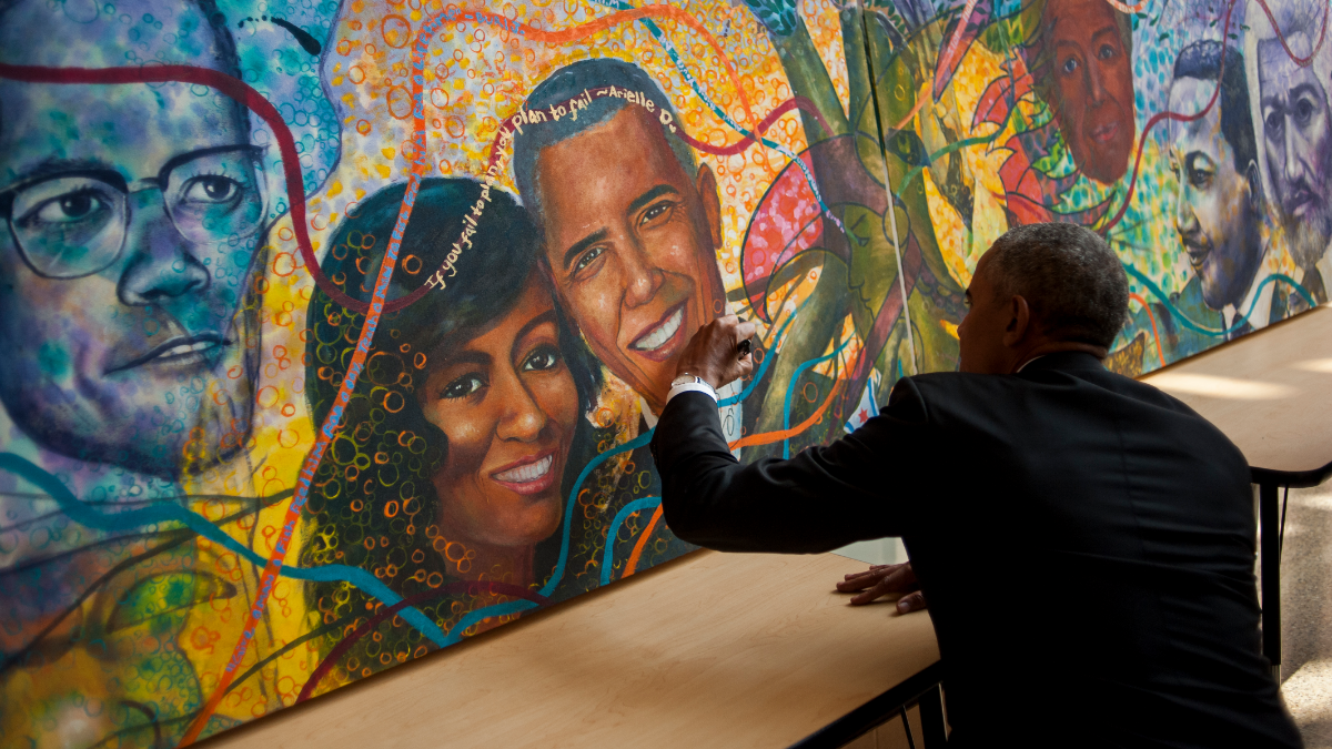 Former President Barack Obama signs a mural in the lobby of Solorio Academy High School that includes him and Michelle Obama. (Bill Healy/WBEZ)