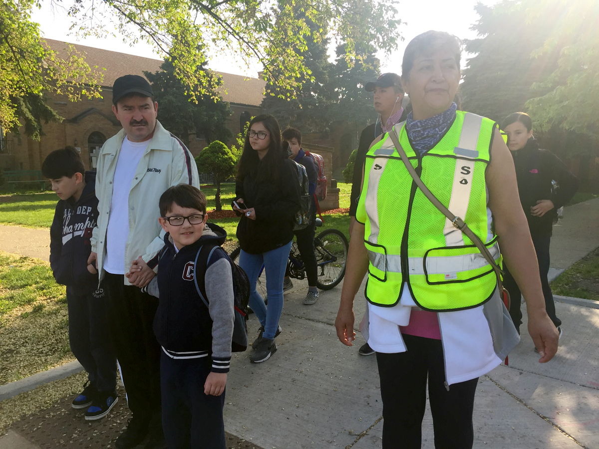 Estela Vásquez ayuda a estudiantes y padres a cruzar la avenida Kedzie, en la calle 46. Solía haber una señal de stop en la intersección, pero fue derribada y, hasta el día de hoy aún no ha sido reemplazada. (Adriana Cardona-Maguigad/WBEZ)