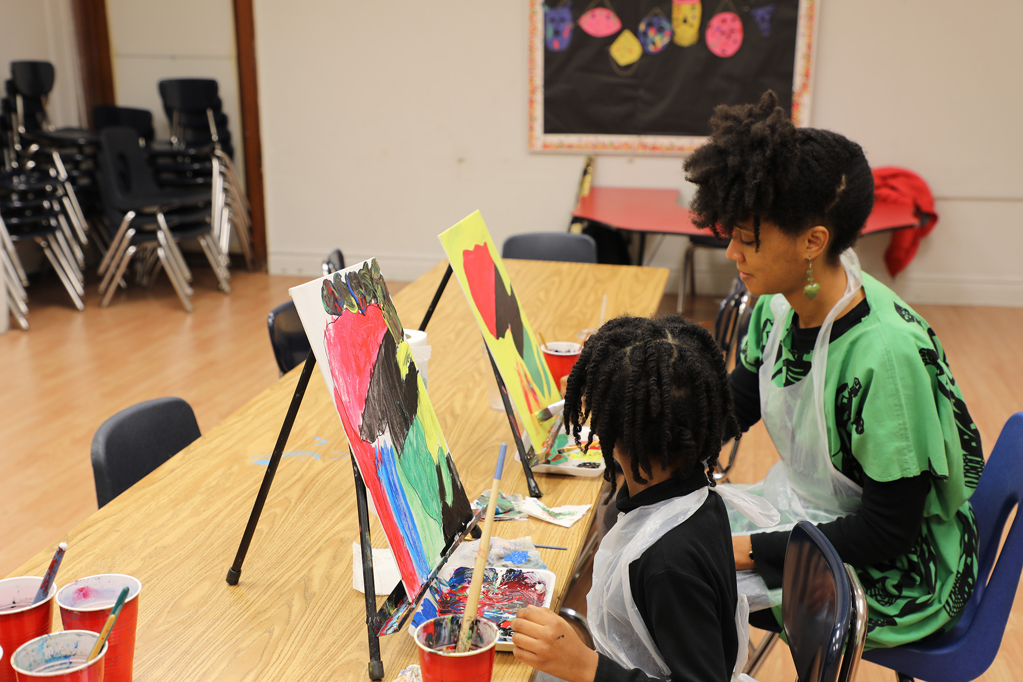 Lecretia Akines and her daughter paint during the Super Karamu event. (Arionne Nettles/WBEZ)