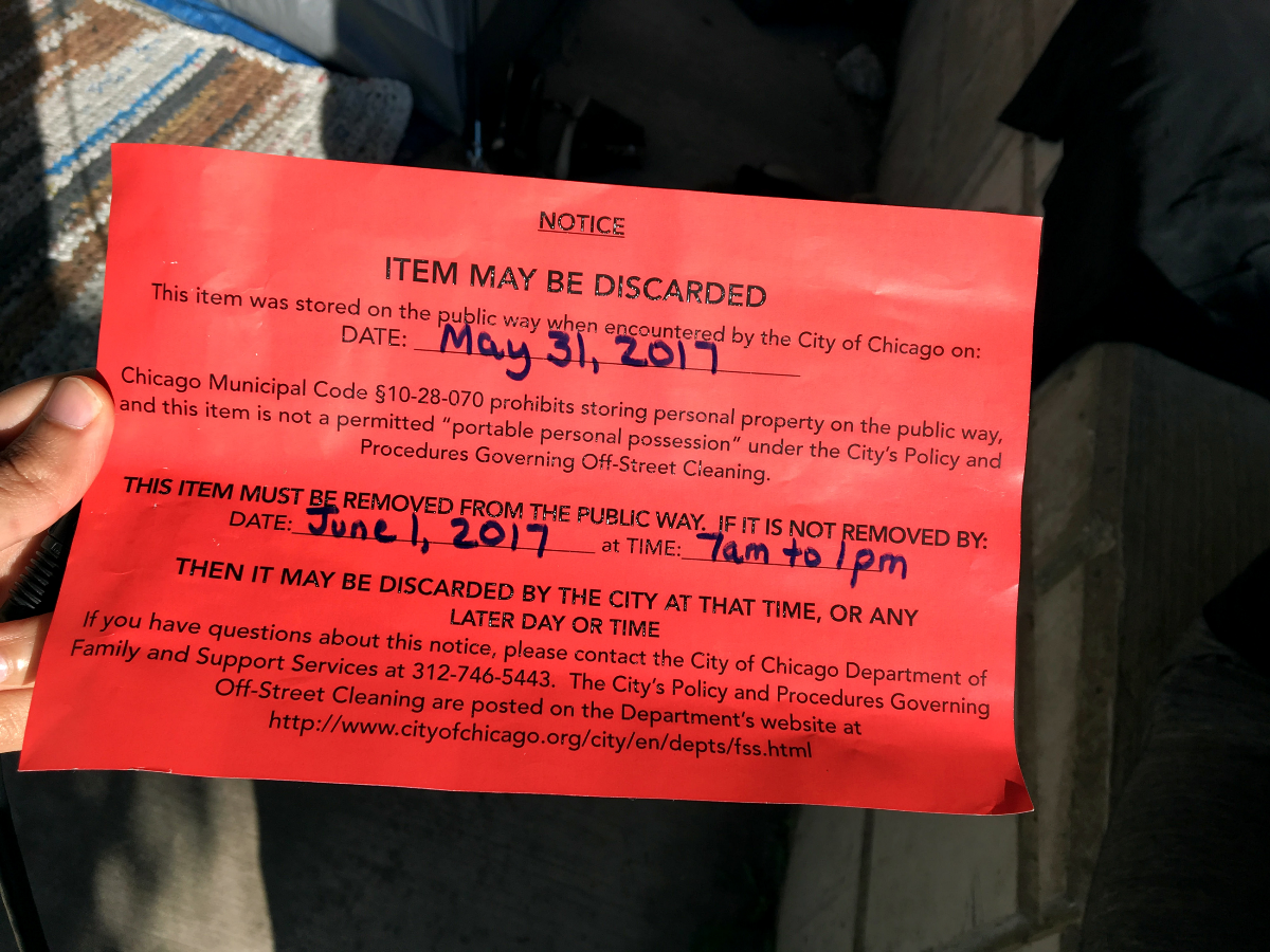 Shawn Smith and Amie Moore said Chicago police officers regularly visit them to post these notices of intention to remove the couple’s tent. The notices cite municipal ordinance and a non-binding agreement on sidewalk cleaning policies as reasons for confiscating the couple’s property. (Odette Yousef/WBEZ)